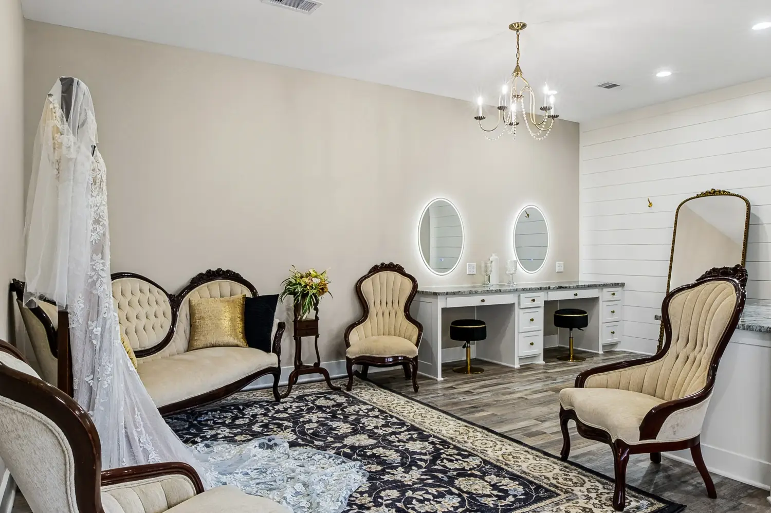 Light-filled bridal suite with vintage seating and illuminated vanity mirrors